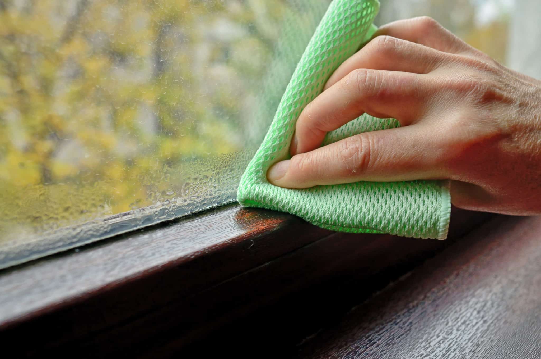 Woman cleaning condensation on double pane window
