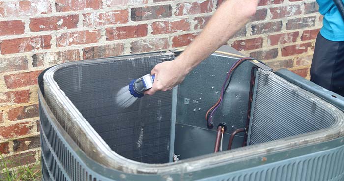 Image; An HVAC technician cleaning the condenser coils.