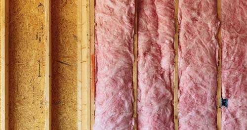 Image: rolls of insulation being installed in an attic.