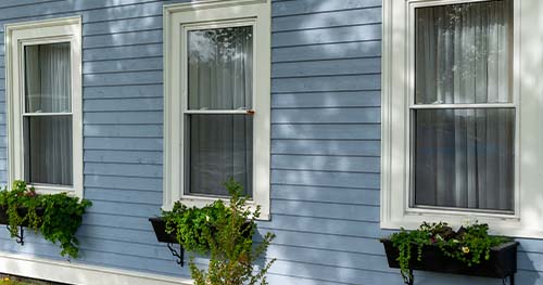 Image: three double hung windows on a blue house.