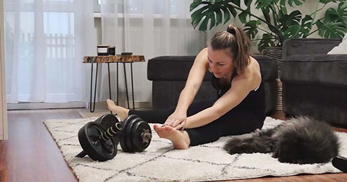 Image: a woman and her cat stretching before a home workout.