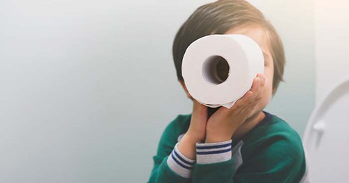 Image: a child playing with a roll of toilet paper.